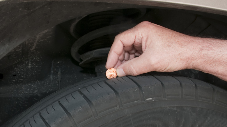 Hand inserting penny on the groove of a tire