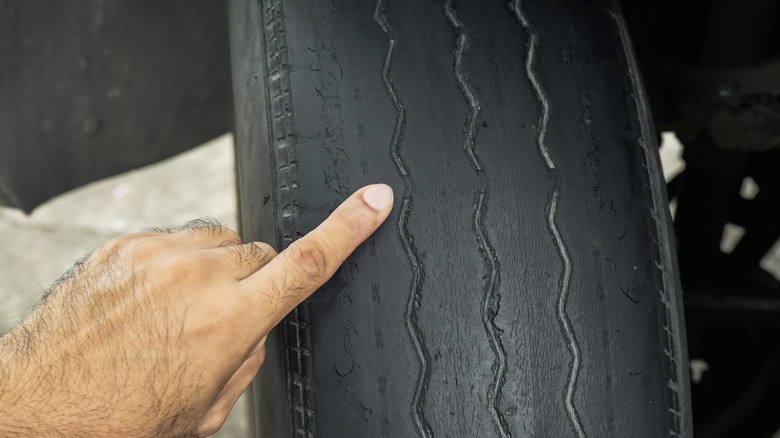 Hand pointing to tire wear bars