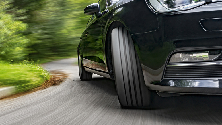 Car speeding on a curved road showing front tire turning