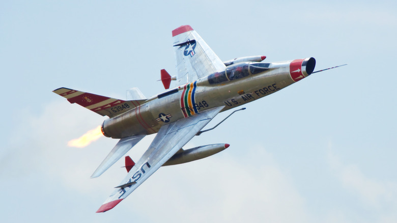 An F-100 jet flying against a blue sky.