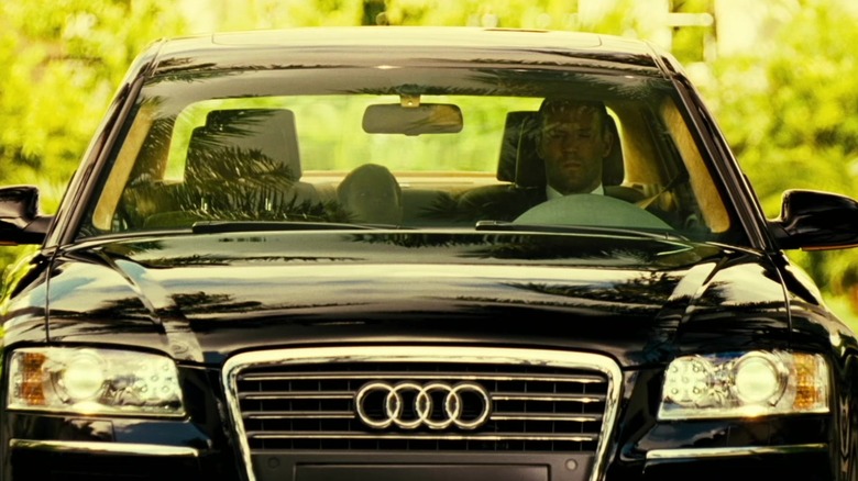 Jason Statham sitting in a black Audi A8L