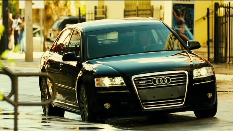 Jason Statham sitting in a black Audi A8