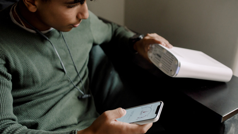 Man looking at Wi-Fi router while holding phone