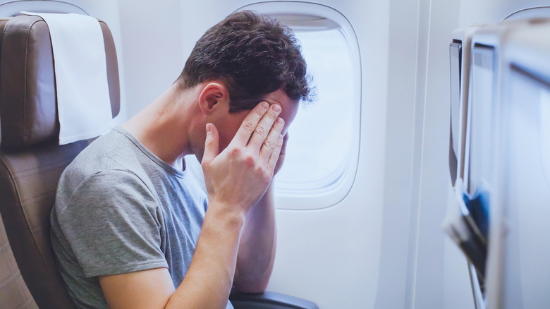 person on plane with head in hands