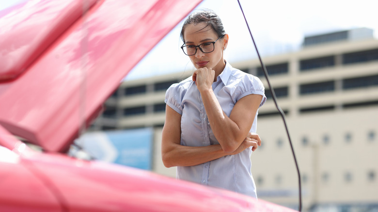 Pensive woman looks at car engine