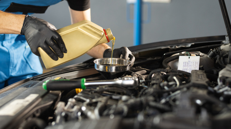 Mechanic pouring oil into engine