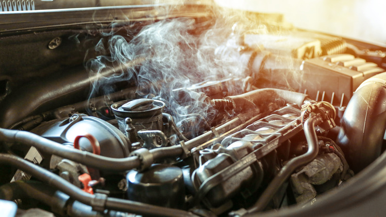 Vehicle engine overheating close up covered in smoke