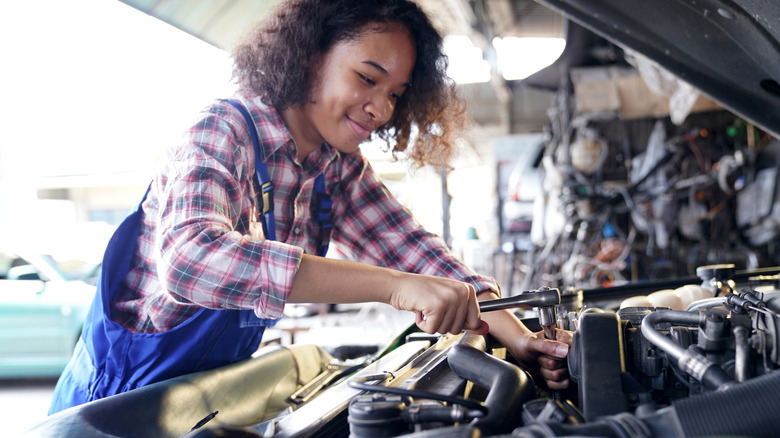 Woman working on car engine