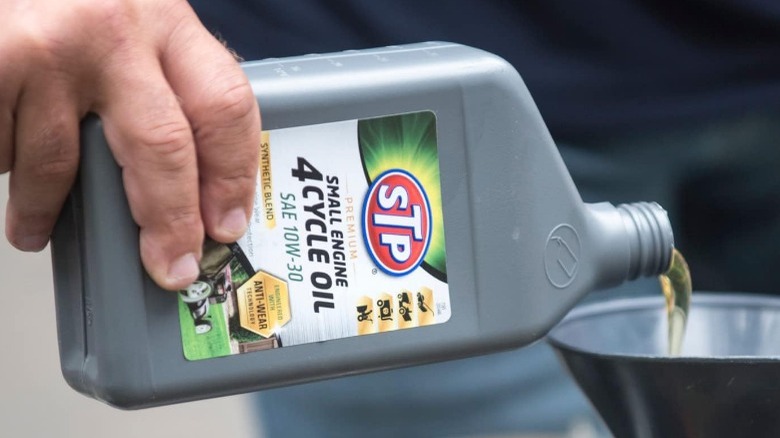 Person pouring mower oil