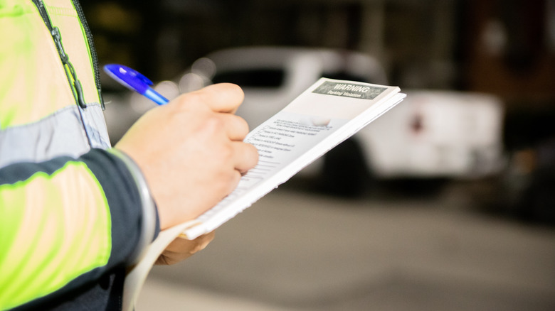 A security guard is giving a parking ticket