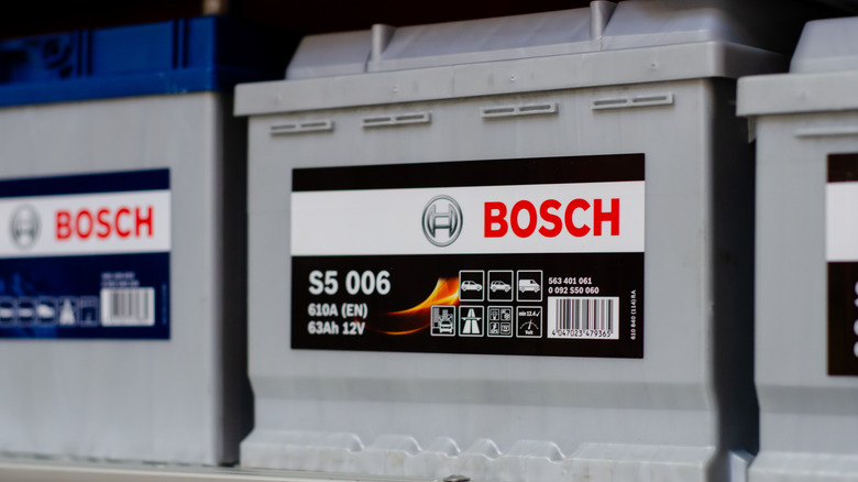 A row of gray Bosch automotive batteries on a shelf.