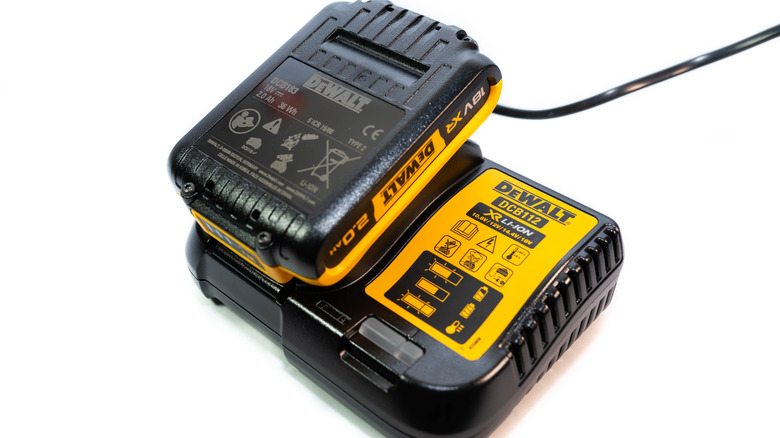 A DeWalt DCB112 12V-20v battery charger and a lithium-ion battery pack placed on top of it