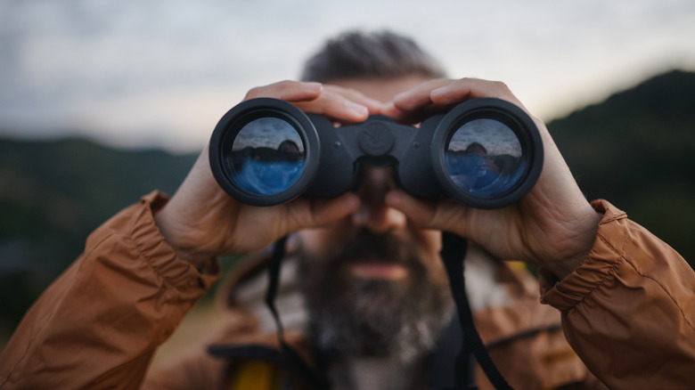 A man looking through binoculars