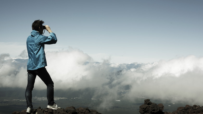 A man looking through binoculars on a mountain top