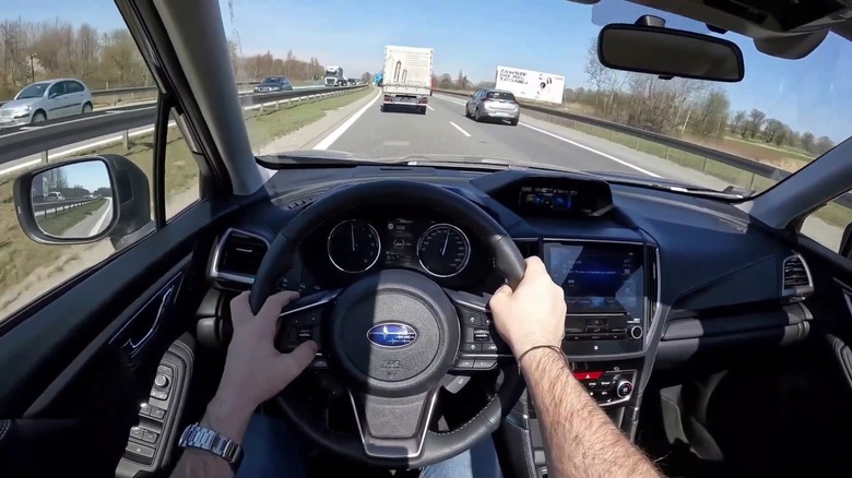 A driver on a highway behind the wheel of a Subaru