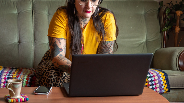 A woman in yellow using a laptop in the living room