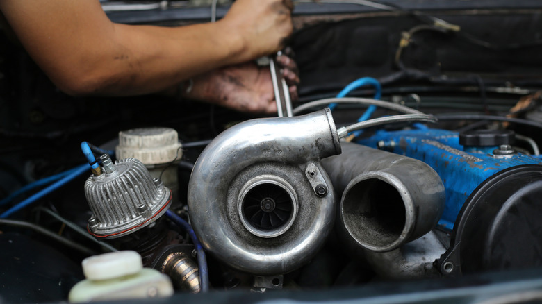 Mechanic repairing a turbo engine with a wrench