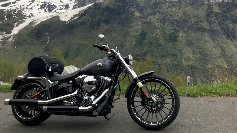 A Harley-Davidson motorcycle parked on a mountain road with snowy peaks in the background