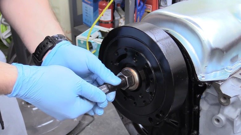 person installing a new harmonic balancer