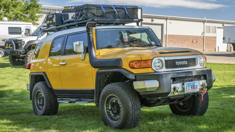 Yellow FJ Cruiser with camping gear parked on grass