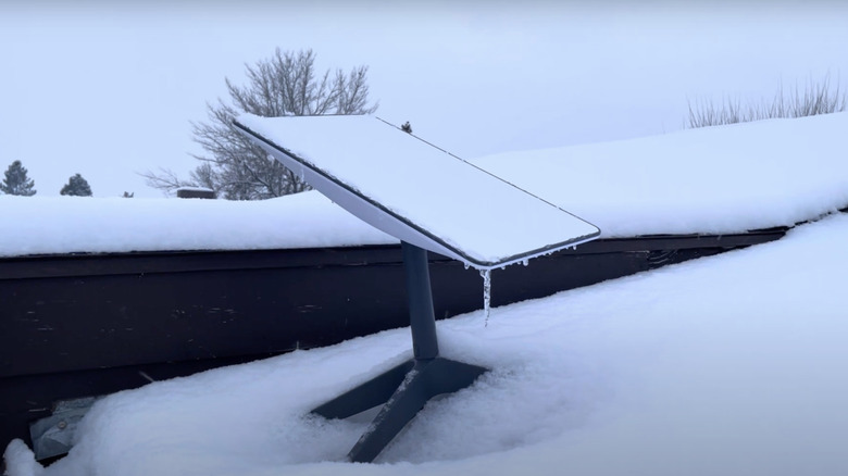 Starlink sitting on snowy roof with ice hanging off it