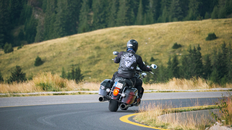 A lone motorcyclist rounding a turn with South Side on the back of a black jacket