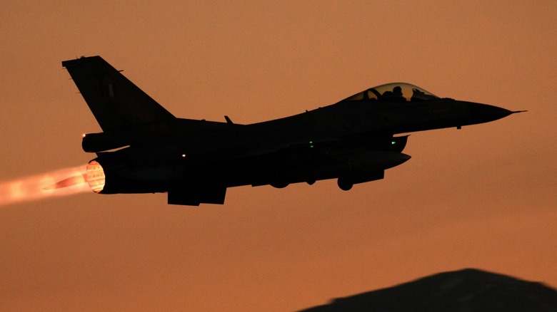 an F-16 Fighting Falcon taking off on afterburners in the sunset