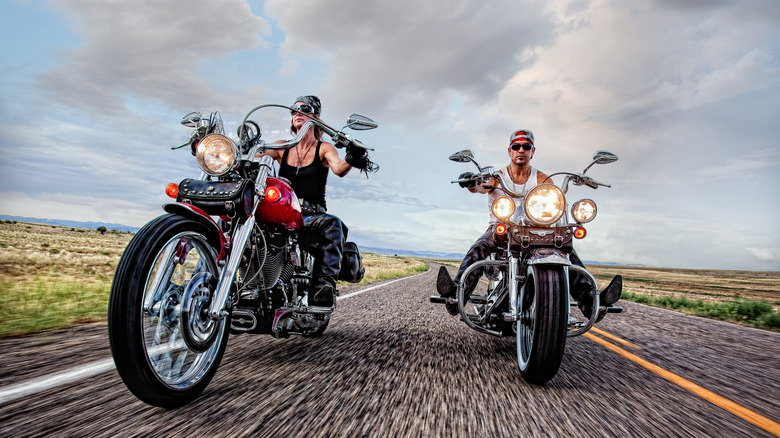 Two people riding motorcycles down the road