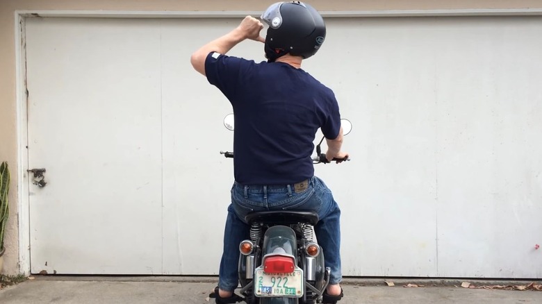 Biker with his left thumb pointing toward his mouth