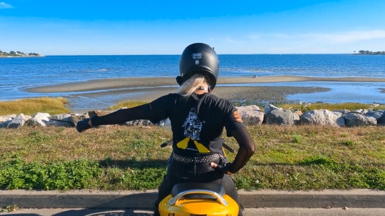 A rider holding a fist out with an ocean in the background