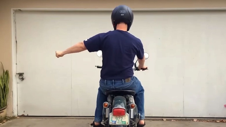 A man seated on a motorcycle holding his fist out