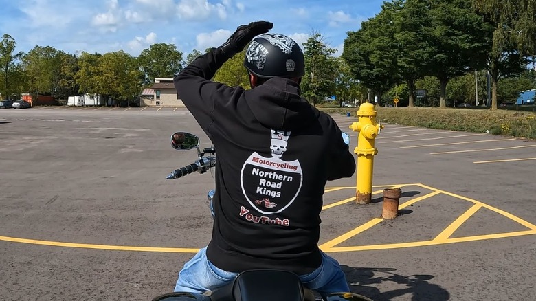 A motorcyclist tapping the top of his helmet