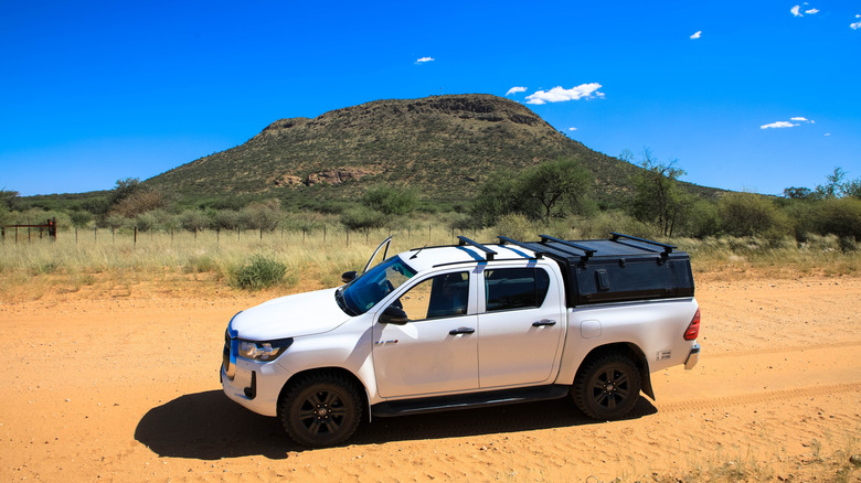 White pickup truck driving off-road on dry dirt