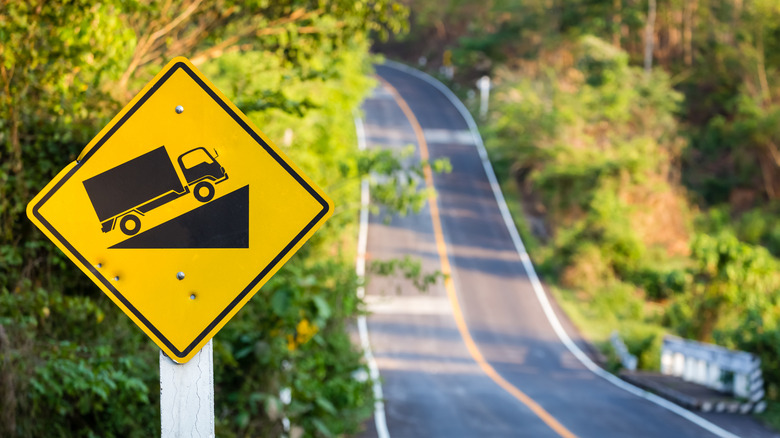 Steep grade traffic sign on the roadside, uphill asphalt road in countryside