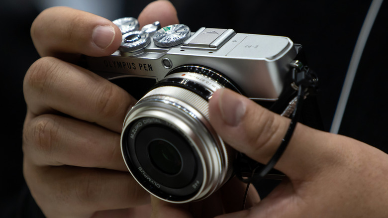 person holding Olympus camera