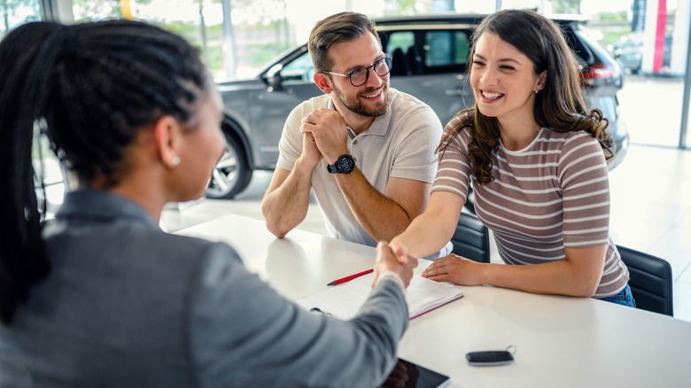 A couple meeting with a salesperson at a car showroom