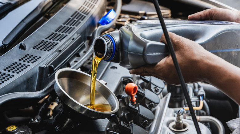 Mechanic pouring oil in an engine