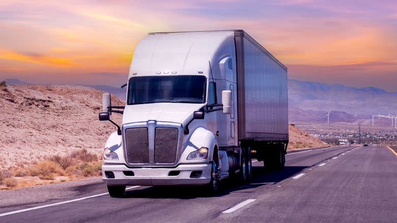 White semi-truck driving during sunset