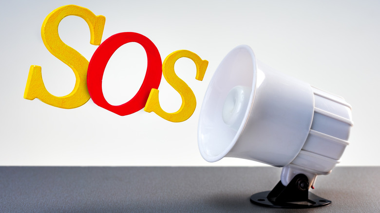 Megaphone on the table with word sos on grey background.