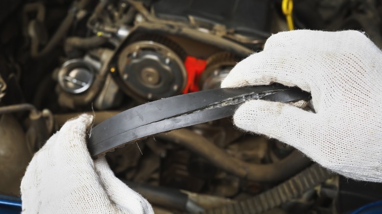 A person holding a damaged car timing belt