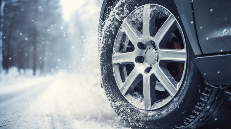 A close-up photo of a car's rear tire driving on snowy terrain