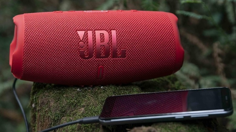 Red JBL speaker charging Android phone using USB cable