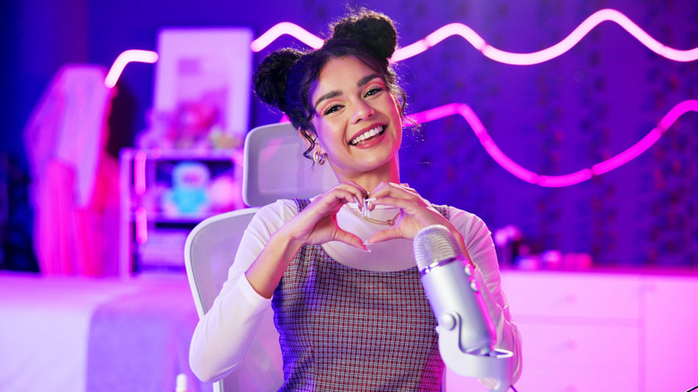 A streamer making a heart gesture using her hands.