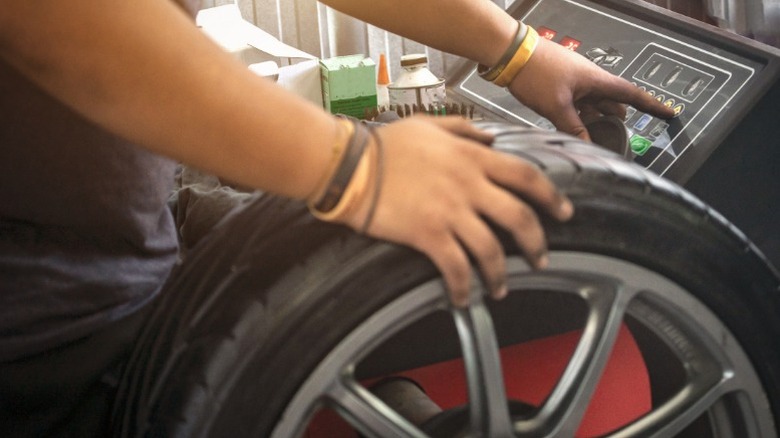 A person using a tire balancing machine to balance a car tire