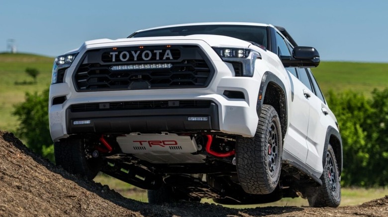 A white 2025Toyota Sequoia TRD Pro off-roading with one tire in the air.