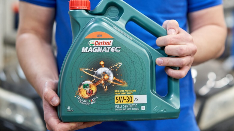 a person holding a jug of castrol 5w-30 engine oil