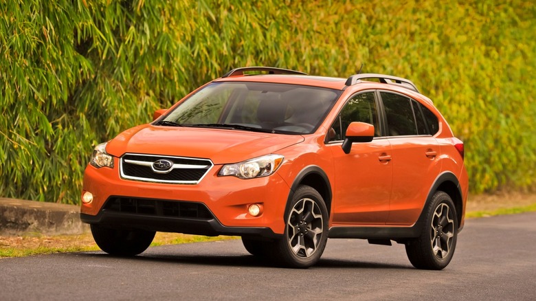 Orange Subaru XV Crosstrek parked on a road with trees on the side