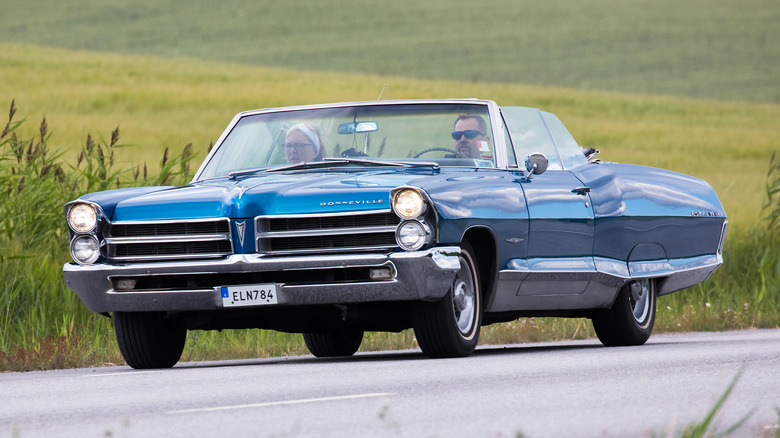 1965 Pontiac Bonneville with couple driving on road