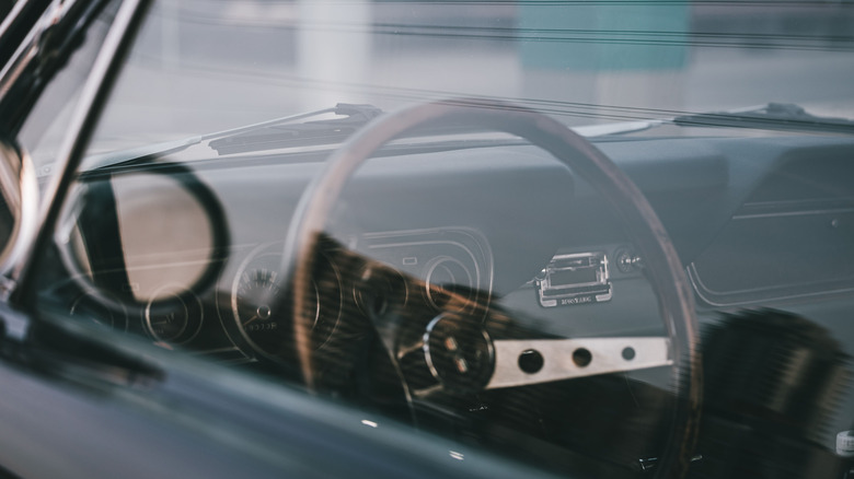 close up photo of 1960s Ford Mustang steering wheel and dashboard behind glass