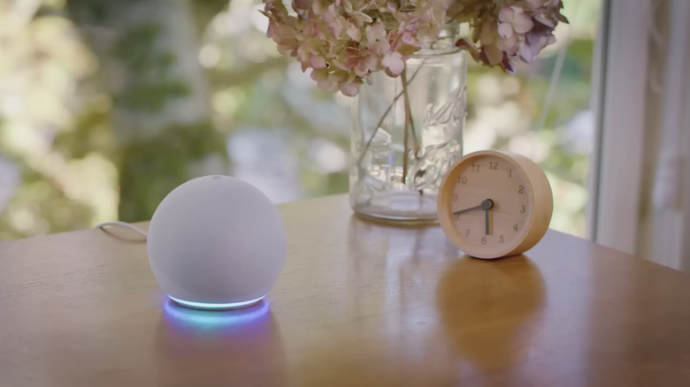 Amazon Echo speaker on table glowing blue while broadcasting announcement